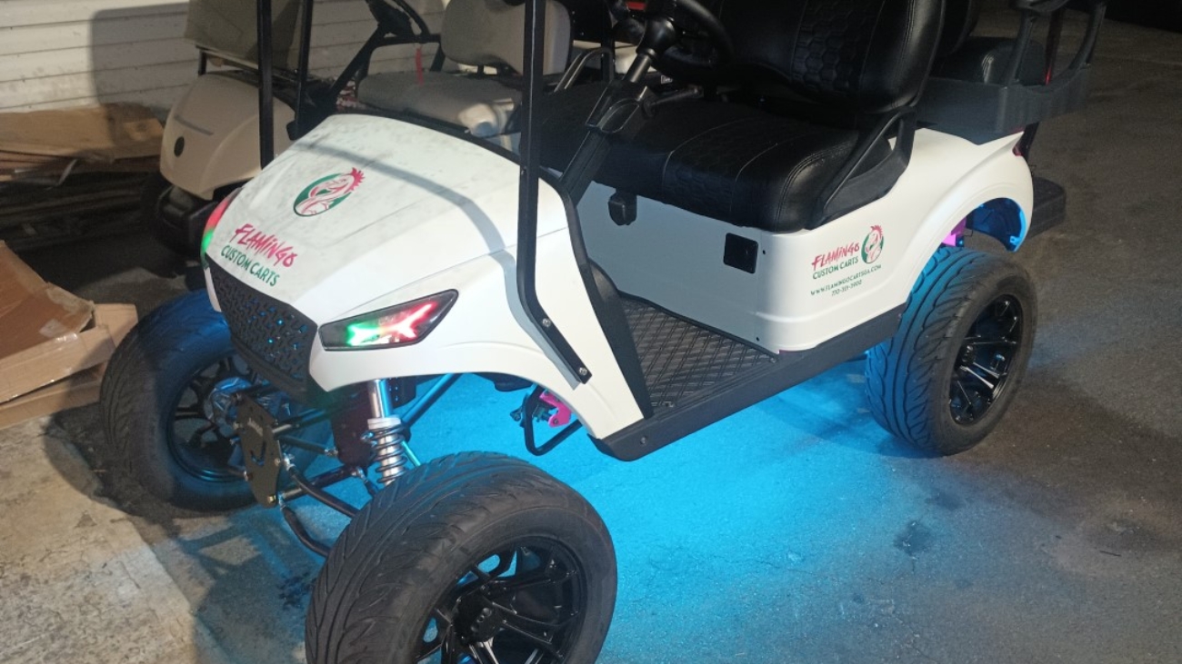 Customized white golf cart with LED lighting and Flamingos Custom Carts branding.