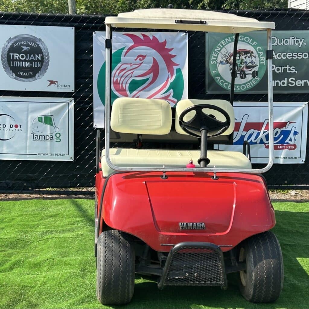 Red Yamaha 2 passenger golf cart with new tires and windshield.