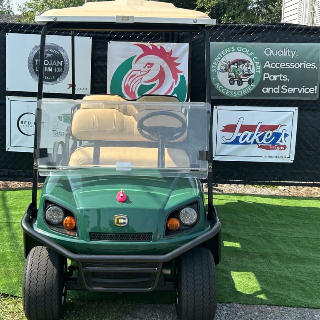 Green Cushman Shuttle 6 golf cart with branded signage and accessories.